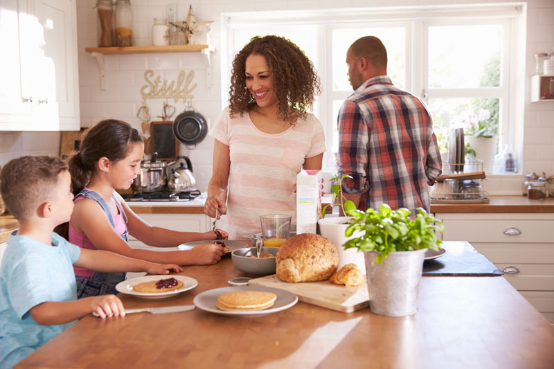 Famille en train de prendre le petit dejeuner dans la cuisine avec des sacs a pain